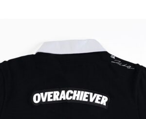 A close up of the overachiever logo on a black shirt